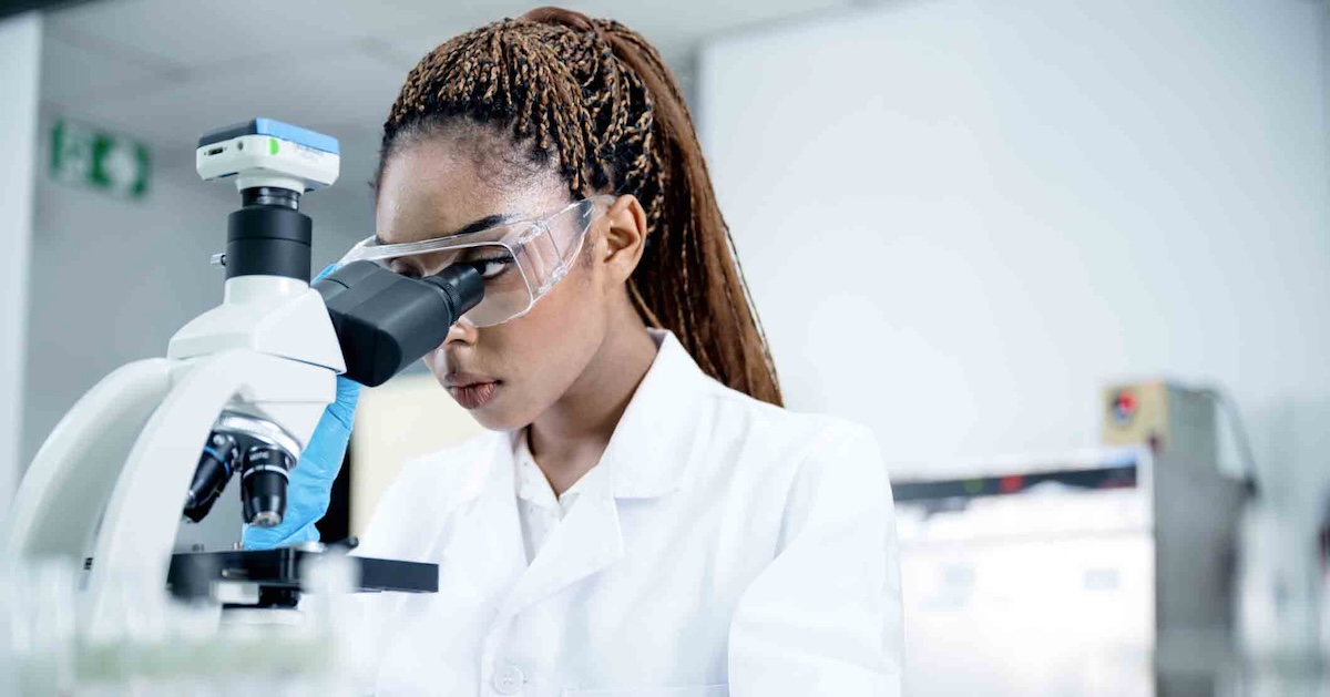 Scientist in a lab looking through a microscope Scientist in a lab looking through a microscope