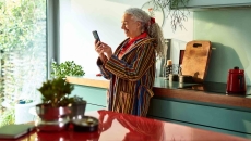 Person standing in their kitchen looking at the phone Person standing in their kitchen looking at the phone