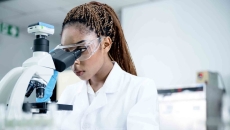 Scientist in a lab looking through a microscope Scientist in a lab looking through a microscope