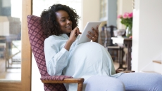 Pregnant person sitting in a chair, looking at a tablet Pregnant person sitting in a chair, looking at a tablet