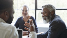 Three business people sitting around a table and talking Three business people sitting around a table and talking