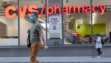 A masked person walking by a CVS pharmacy. A masked person walking by a CVS pharmacy.