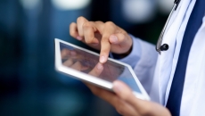 Healthcare provider holding a tablet while wearing a lab coat and stethoscope Healthcare provider holding a tablet while wearing a lab coat and stethoscope