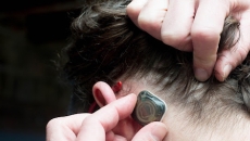 A person pulling back their hair to place the sensor A person pulling back their hair to place the sensor