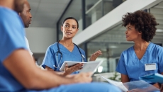 Three healthcare providers sitting in a circle and talking to each other Three healthcare providers sitting in a circle and talking to each other