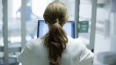 Person sitting at a computer with their back turned Person sitting at a computer with their back turned