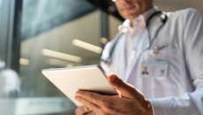 A doctor holding a digital tablet reviewing a patient's record A doctor holding a digital tablet reviewing a patient's record