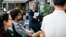 Numerous individuals sitting in a half circle looking at something off-screen Numerous individuals sitting in a half circle looking at something off-screen