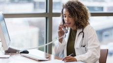 Healthcare provider on the phone while sitting at a desk with a computer on it