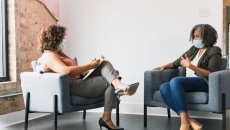 Two people seated, wearing masks
