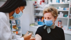 Person sitting in a pharmacy and getting an injection by a pharmacist Person sitting in a pharmacy and getting an injection by a pharmacist