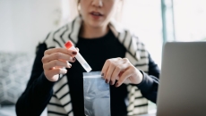 person with vial in front of computer monitor