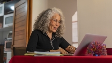 Person sitting at a table with a red table cloth on it while in a home looking at a computer Person sitting at a table with a red table cloth on it while in a home looking at a computer