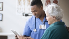 Healthcare provider showing a tablet to a patient Healthcare provider showing a tablet to a patient