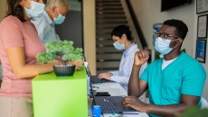 Healthcare providers sitting at a table with two people standing up on the other side Healthcare providers sitting at a table with two people standing up on the other side