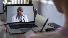 Physician interacting remotely with a person via laptop Physician interacting remotely with a person via laptop
