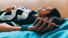 Person lying on a bed while holding a phone Person lying on a bed while holding a phone