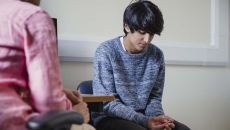 Two people sitting in a room, one with their head down Two people sitting in a room, one with their head down