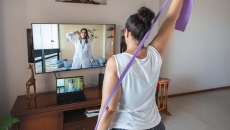 A woman doing exercises guided by a physical therapist on her screen A woman doing exercises guided by a physical therapist on her screen