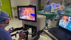 A surgeon operating while other clinicians follow along on a laptop using Proximie's platform A surgeon operating while other clinicians follow along on a laptop using Proximie's platform