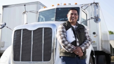 Truck driver standing in front of a semi-truck while holding a clipboard Truck driver standing in front of a semi-truck while holding a clipboard