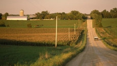 A truck driving on a gravel road near a farm A truck driving on a gravel road near a farm
