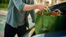 Person putting a bag of groceries from Uber Eats in a car's trunk Person putting a bag of groceries from Uber Eats in a car's trunk