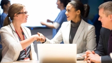 Businesspeople shaking hands in front of a laptop