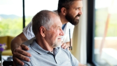 adult caregiver and person look out a window