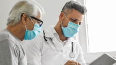 A medical professional and a patient talking to another provider using a tablet. A medical professional and a patient talking to another provider using a tablet.