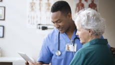 A doctor and a patient looking at information on a tablet. A doctor and a patient looking at information on a tablet.