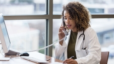 A doctor talking to a patient on a landline phone while taking notes. A doctor talking to a patient on a landline phone while taking notes.