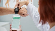 A doctor helping a patient synchronize heart rate data on a smart watch and phone A doctor helping a patient synchronize heart rate data on a smart watch and phone