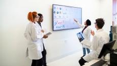 A group of providers or researchers looking at a data dashboard on a large TV on a wall A group of providers or researchers looking at a data dashboard on a large TV on a wall
