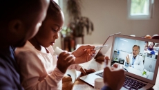 A father and daughter talking to a doctor through a video chat on a laptop. A father and daughter talking to a doctor through a video chat on a laptop.