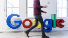 A person walking past a Google sign in an office A person walking past a Google sign in an office