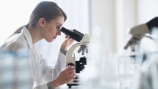 A researcher using a microscope in a lab A researcher using a microscope in a lab
