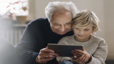 An older man and a child using a tablet An older man and a child using a tablet