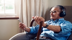 A person wearing headphones, using a smartphone and wearing a watch in the home A person wearing headphones, using a smartphone and wearing a watch in the home