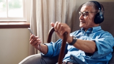 An older man using a smartphone and wearing headphones An older man using a smartphone and wearing headphones