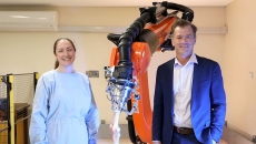 University of Sydney professors Elizabeth Clarke and Bill Walter pose beside the robotic arm KOBRA