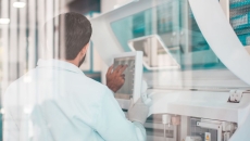 Person standing with their back turned while looking at a computer next while in a lab