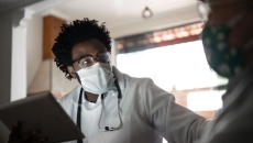 Healthcare provider with a stethoscope around their neck talking to a patient