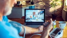 A doctor on screen guiding a patient measuring their blood pressure remotely