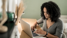 A woman using a laptop with a spreadsheet on her desk. A woman using a laptop with a spreadsheet on her desk.