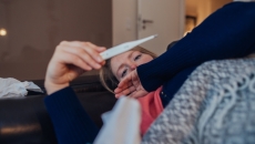 A sick person looking at a thermometer A sick person looking at a thermometer