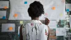 A woman at work standing in front of a wall with papers and planning documents A woman at work standing in front of a wall with papers and planning documents