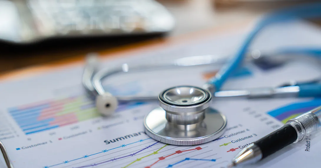 Financial report on a desk with a stethoscope on top Financial report on a desk with a stethoscope on top