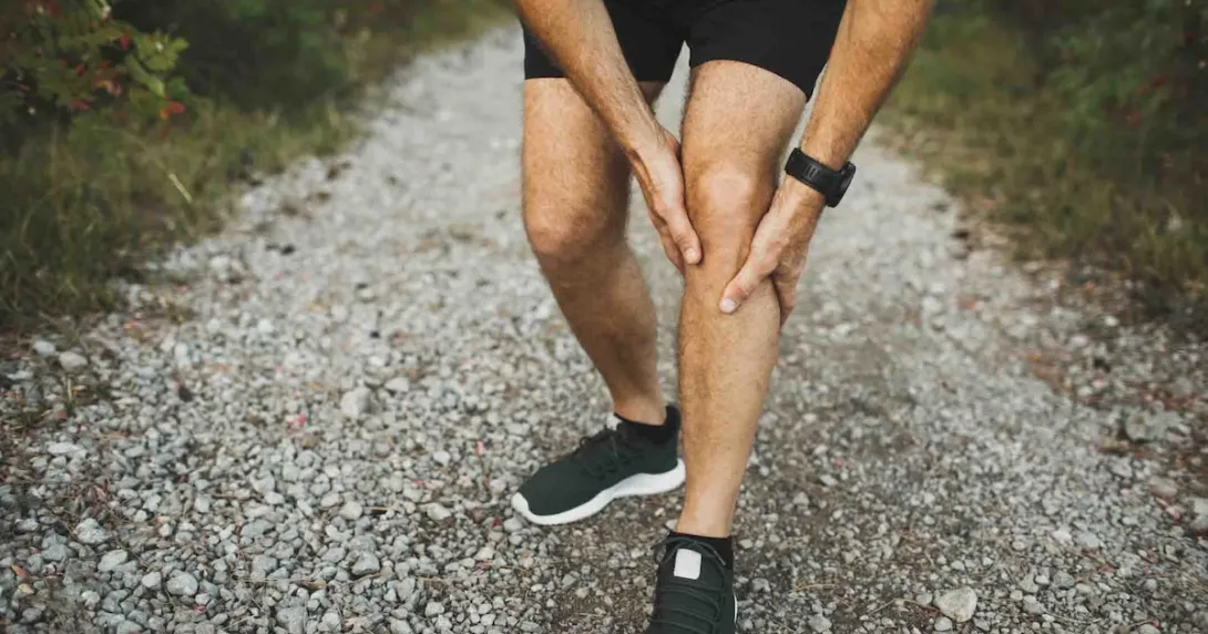 Person holding onto their leg while in the wilderness Person holding onto their leg while in the wilderness