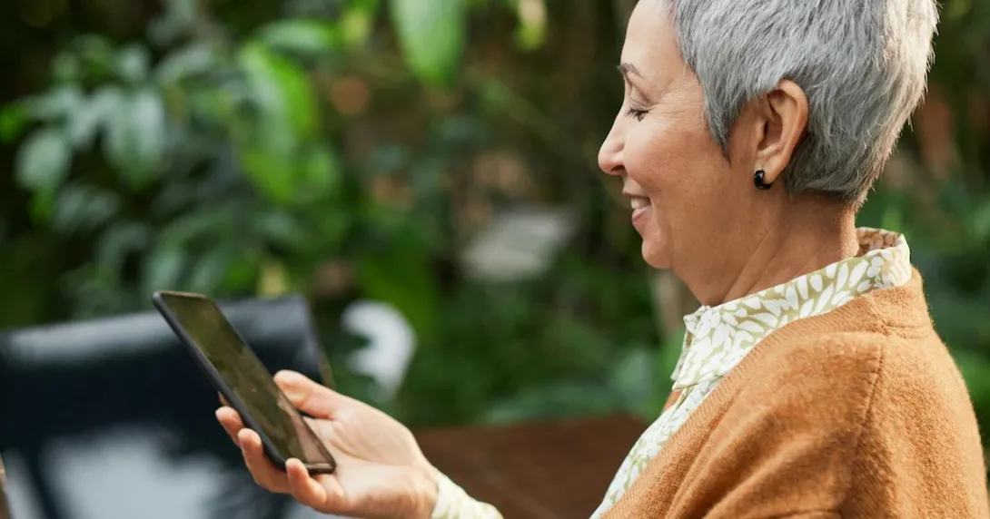 A smiling elderly person using a smartphone A smiling elderly person using a smartphone